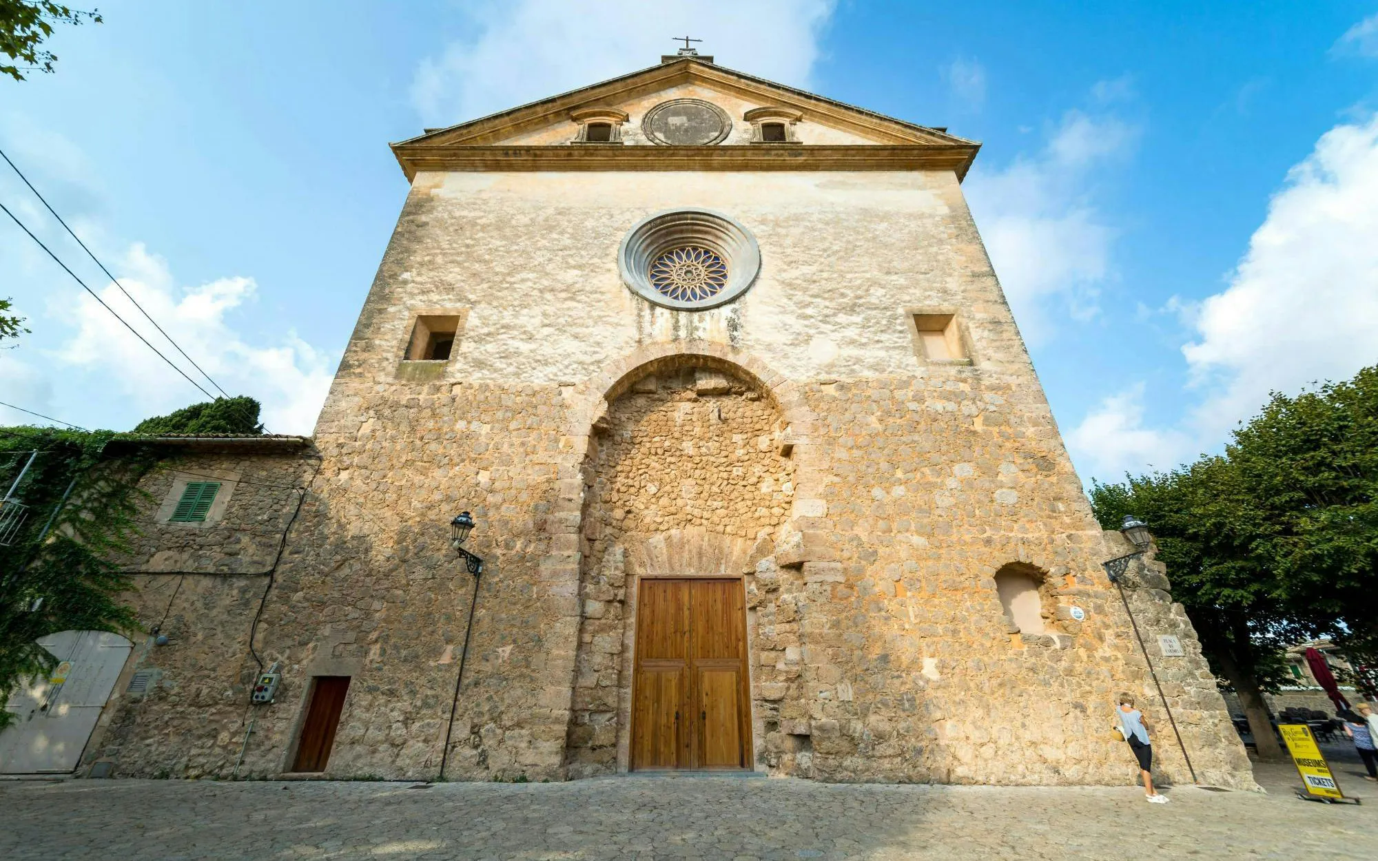 Church of San Bartolomé facade in Valldemossa, Mallorca, with stone architecture and circular window.