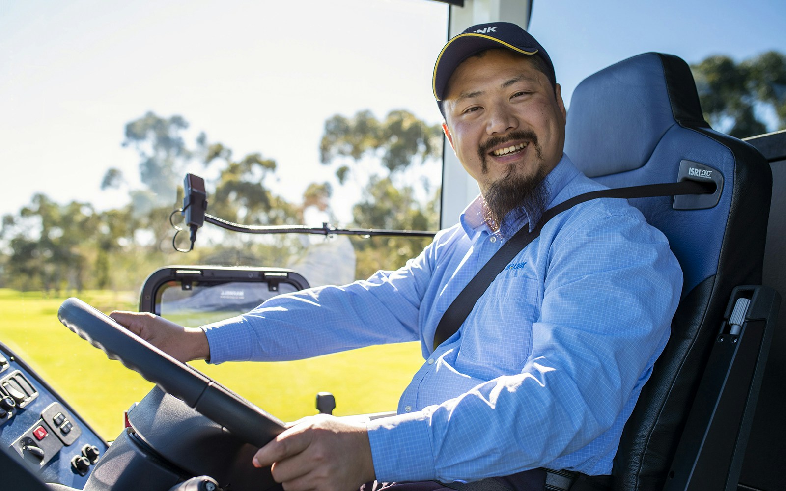 Bus driver smiling while steering through Adelaide Hills tour.