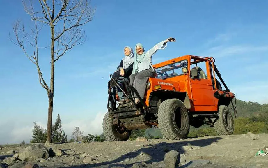 Jeep tour at Merapi with two people enjoying sunrise, rocky terrain, Dubai tour.