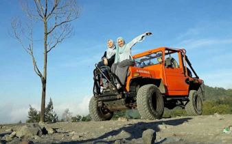 Jeep tour at Merapi with two people enjoying sunrise, rocky terrain, Dubai tour.