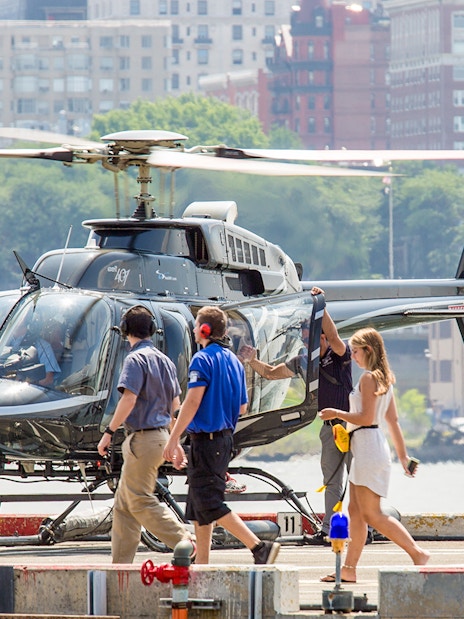 Helicopter on heliport with passengers boarding for 20-minute tour.