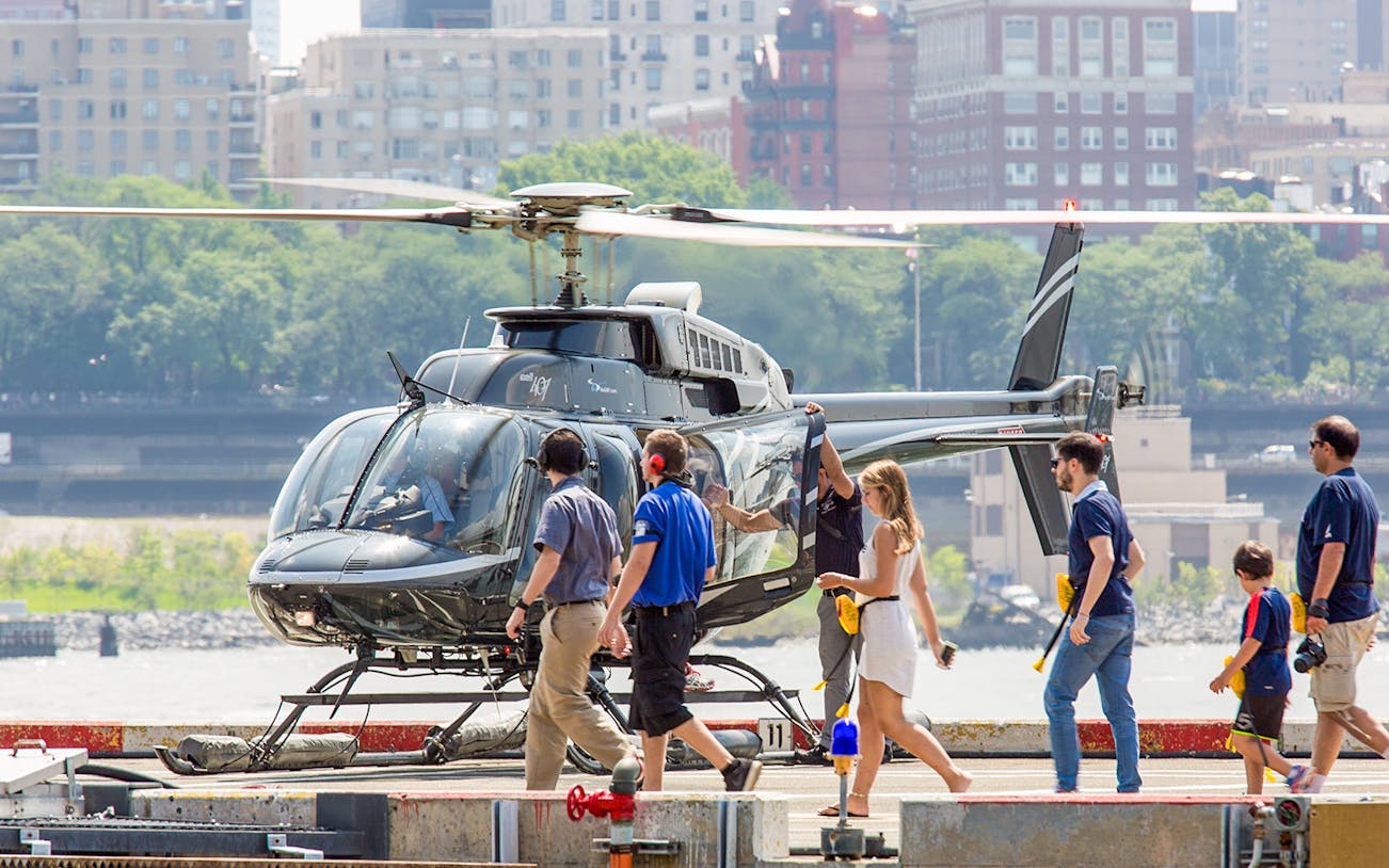 Helicopter on heliport with passengers boarding for 20-minute tour.