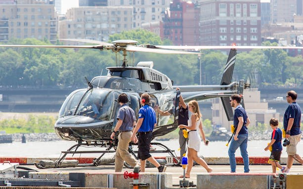 Helicopter on heliport with passengers boarding for 20-minute tour.