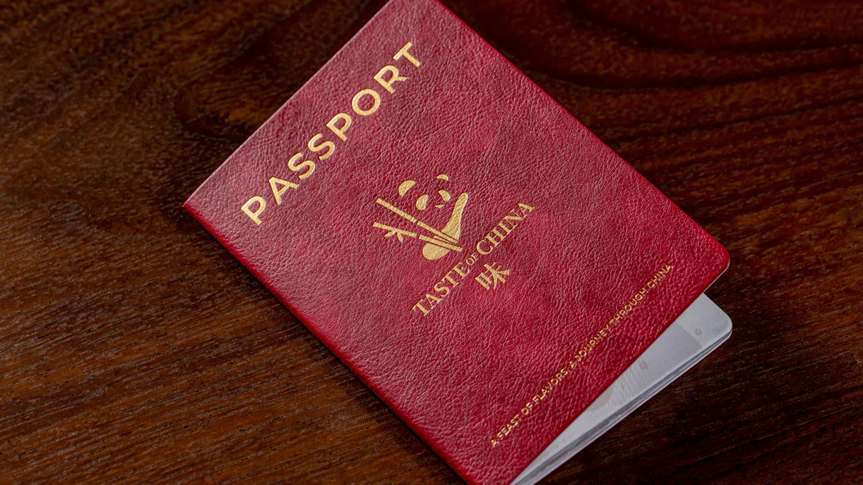 Red passport for "Taste of China" restaurant, Shanghai, on wooden table.
