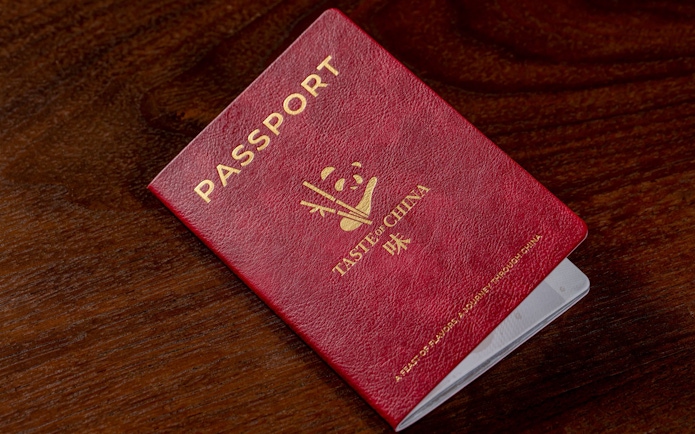 Red passport for "Taste of China" restaurant, Shanghai, on wooden table.