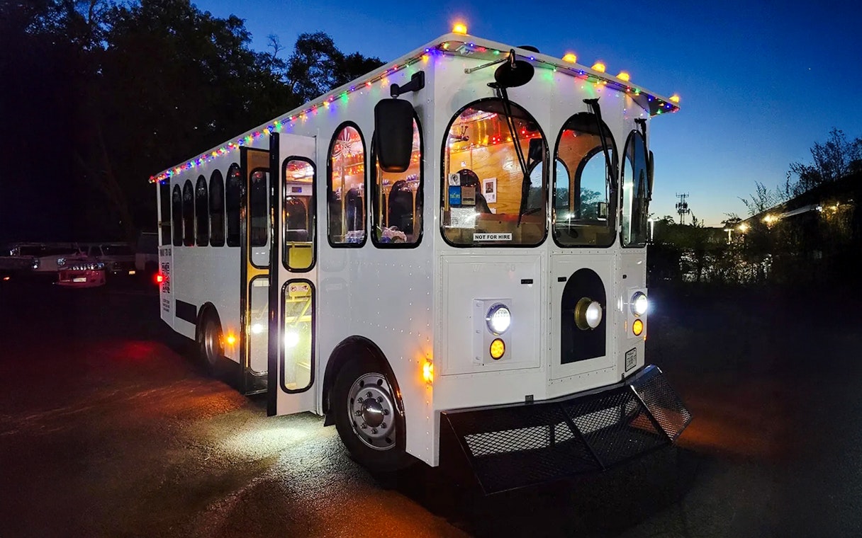 Trolley decorated with holiday lights for Philadelphia tour at dusk.