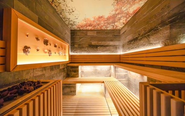 Wooden sauna interior at QC Terme San Pellegrino Spa with warm lighting and decorative elements.