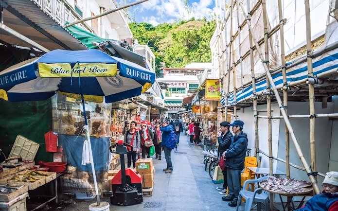 Street market scene on Lantau Island, Hong Kong, with people shopping and local stalls.