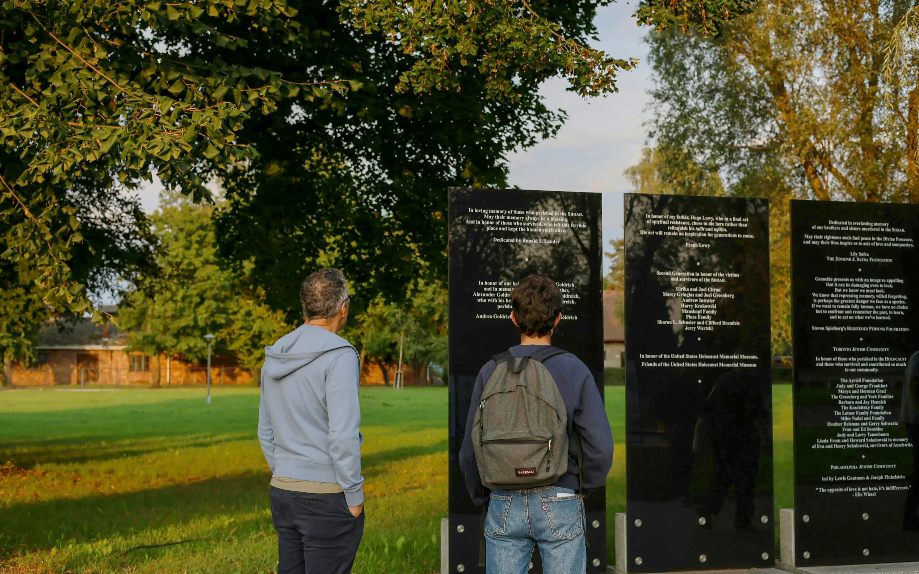 Visitors reading memorial plaques at Auschwitz-Birkenau, Krakow tour site.