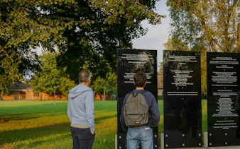 Visitors reading memorial plaques at Auschwitz-Birkenau, Krakow tour site.