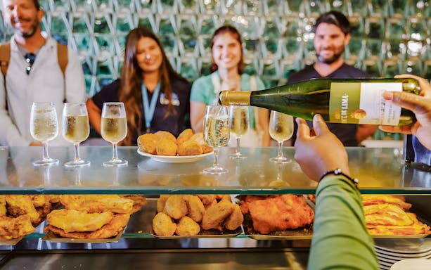 Tourists enjoying wine and snacks during Lisbon Food Walk in Baixa.