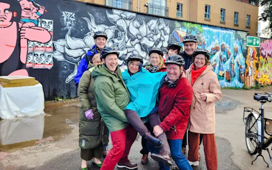 Guests on bikes in front of colorful street art during the Glasgow Highlights Bike Tour.