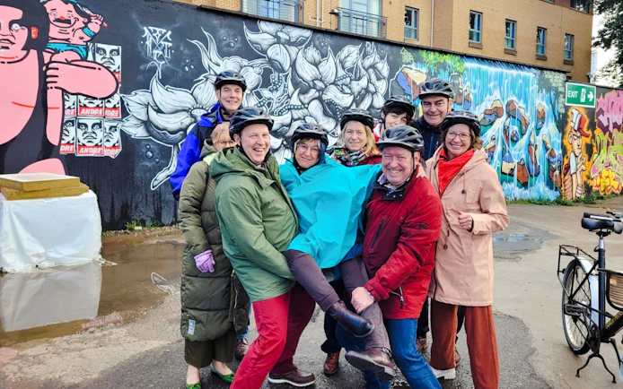 Guests on bikes in front of colorful street art during the Glasgow Highlights Bike Tour.