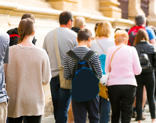 People standing in line outside a historic building, skip-the-line tour option available.