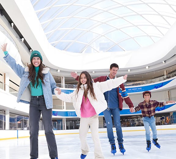 Group ice skating at the American Dream ice rink under a glass dome.