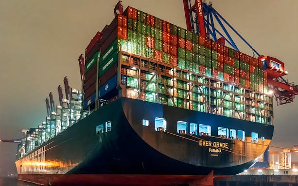 Cargo ship illuminated at night in Grand Harbor during evening lights cruise.