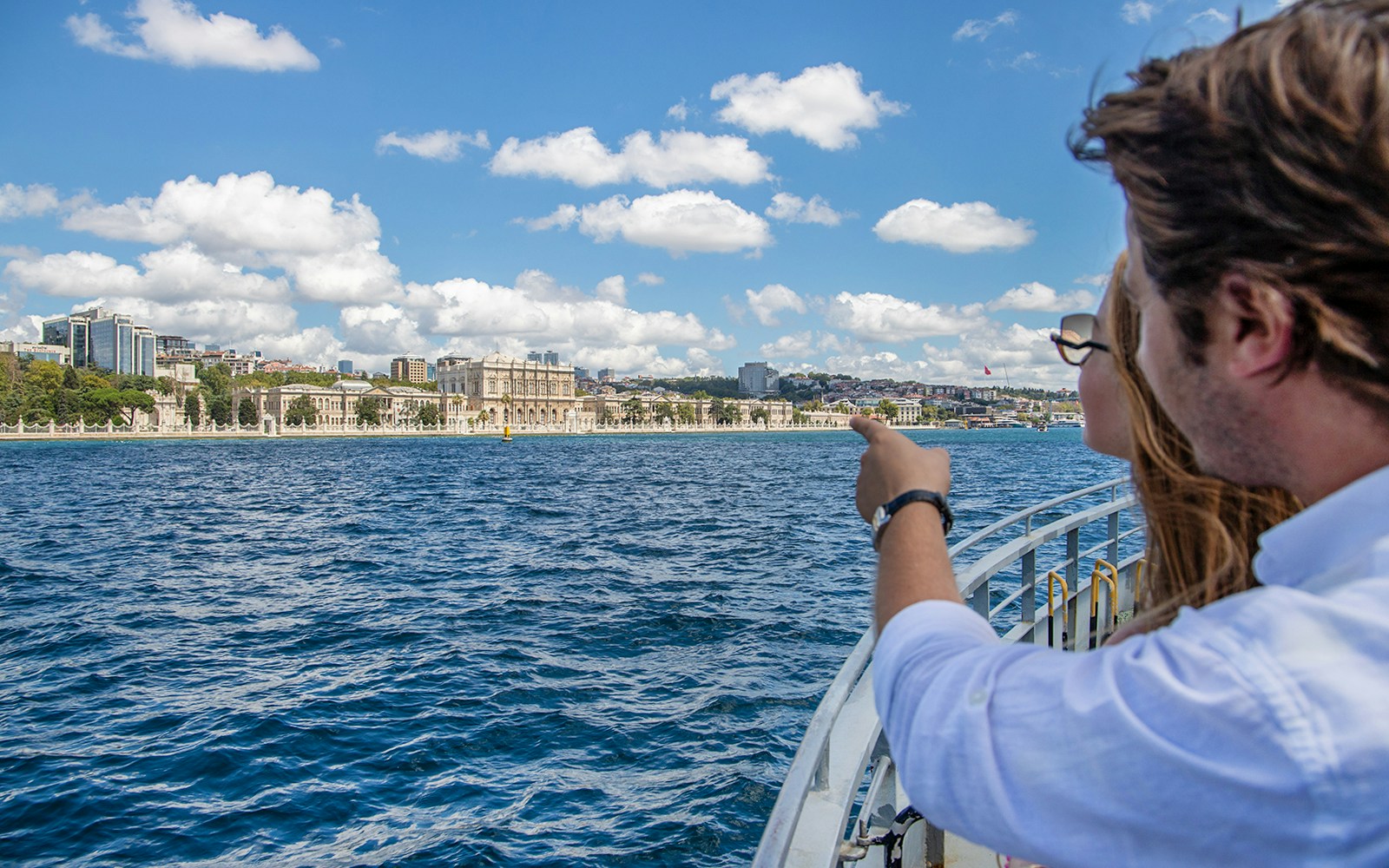 Couple on Bosphorus cruise pointing at Dolmabahçe Palace, Istanbul.