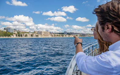 Couple on Bosphorus cruise pointing at Dolmabahçe Palace, Istanbul.