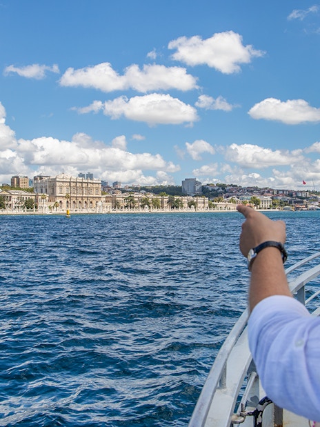 Couple on Bosphorus cruise pointing at Dolmabahçe Palace, Istanbul.