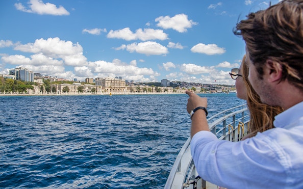 Couple on Bosphorus cruise pointing at Dolmabahçe Palace, Istanbul.