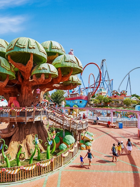 PortAventura theme park with treehouse and roller coasters in the background.
