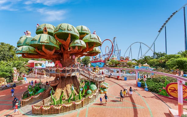 PortAventura theme park with treehouse and roller coasters in the background.