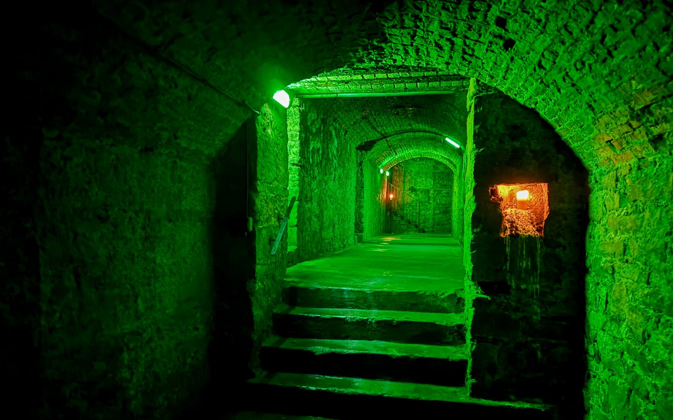 Underground stone corridor with green lighting on the Terror Tour in Edinburgh.