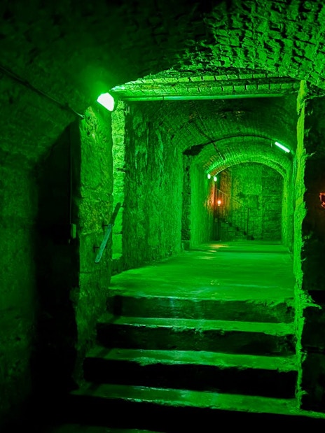 Underground stone corridor with green lighting on the Terror Tour in Edinburgh.
