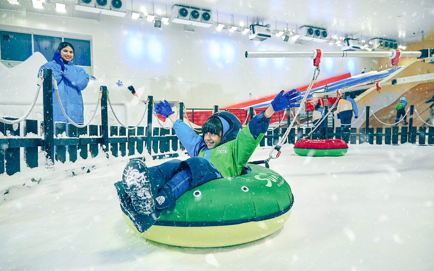 Child enjoying snow tubing at Snow Dunes Theme Park indoor slope.
