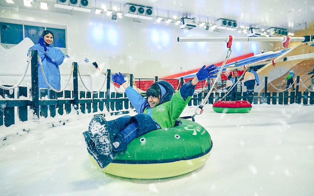 Child enjoying snow tubing at Snow Dunes Theme Park indoor slope.
