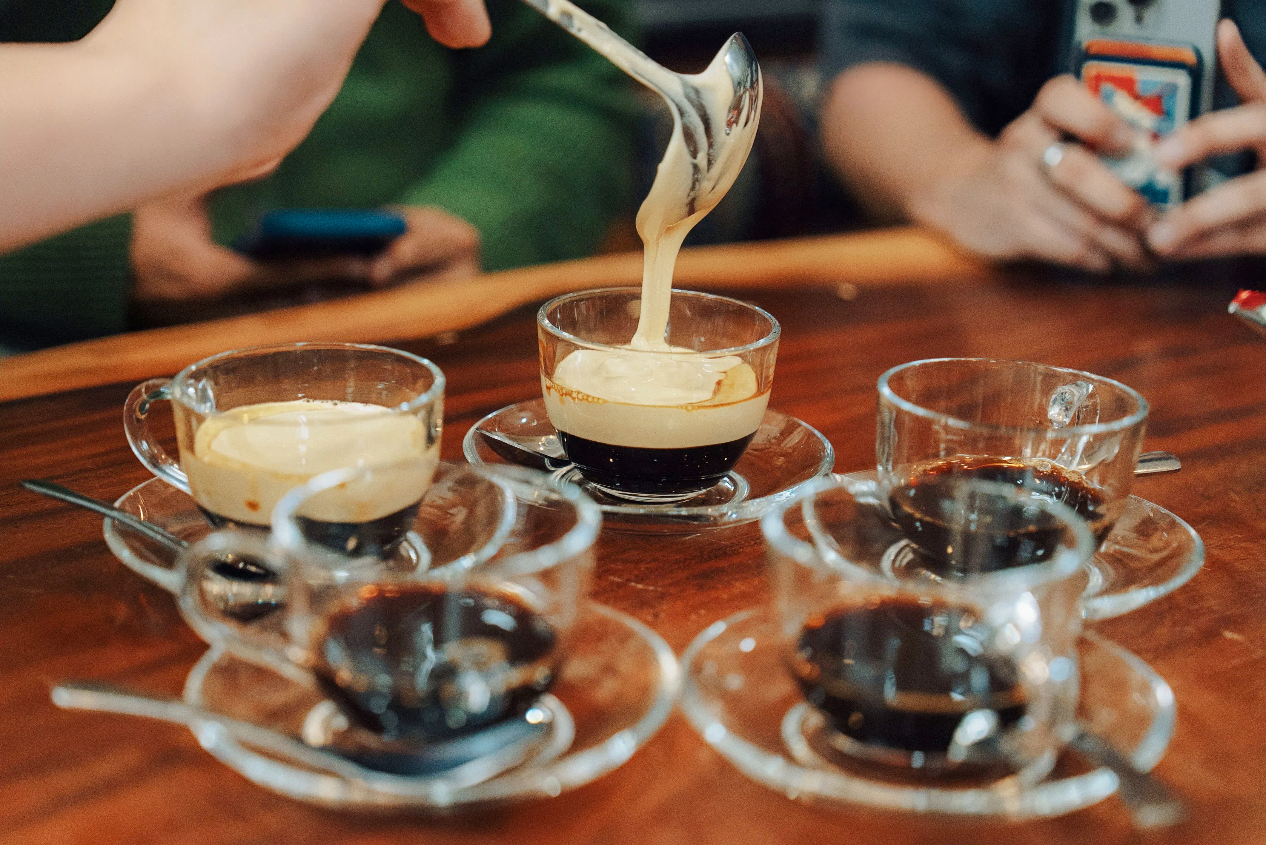 Pouring creamy topping on Vietnamese egg coffee at Hanoi workshop.
