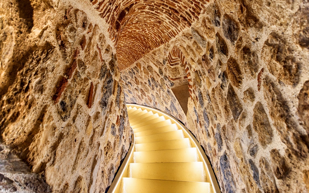 Staircase inside Galata Tower, Istanbul, with stone walls and arched ceiling.