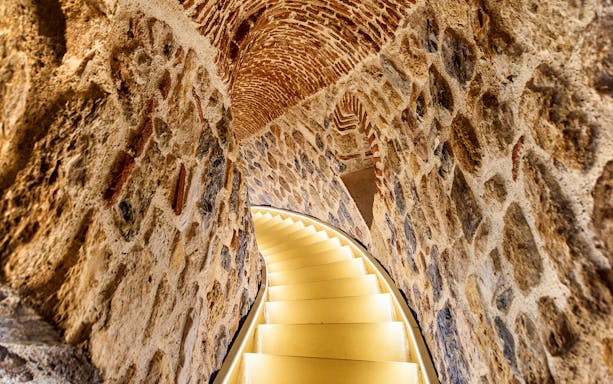 Staircase inside Galata Tower, Istanbul, with stone walls and arched ceiling.