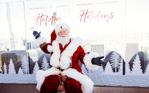 Santa Claus at Rockefeller Center with city skyline, part of the VIP Pass: Holiday Edition experience.