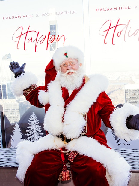 Santa Claus at Rockefeller Center with city skyline, part of the VIP Pass: Holiday Edition experience.
