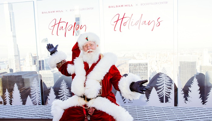 Santa Claus at Rockefeller Center with city skyline, part of the VIP Pass: Holiday Edition experience.