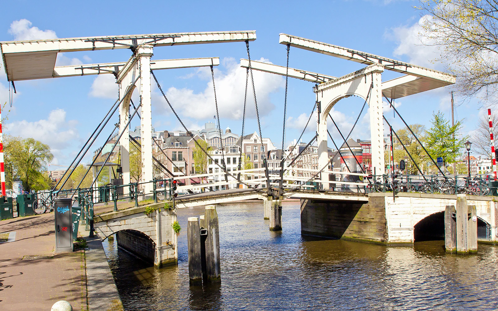 Drawbridge over Nieuwe Herengracht canal in Amsterdam with city buildings in the background.