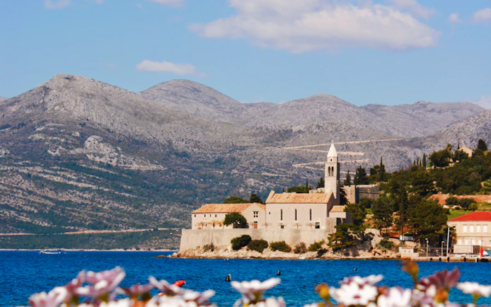Lopud Island, Croatia, with historic church and Adriatic Sea in foreground.
