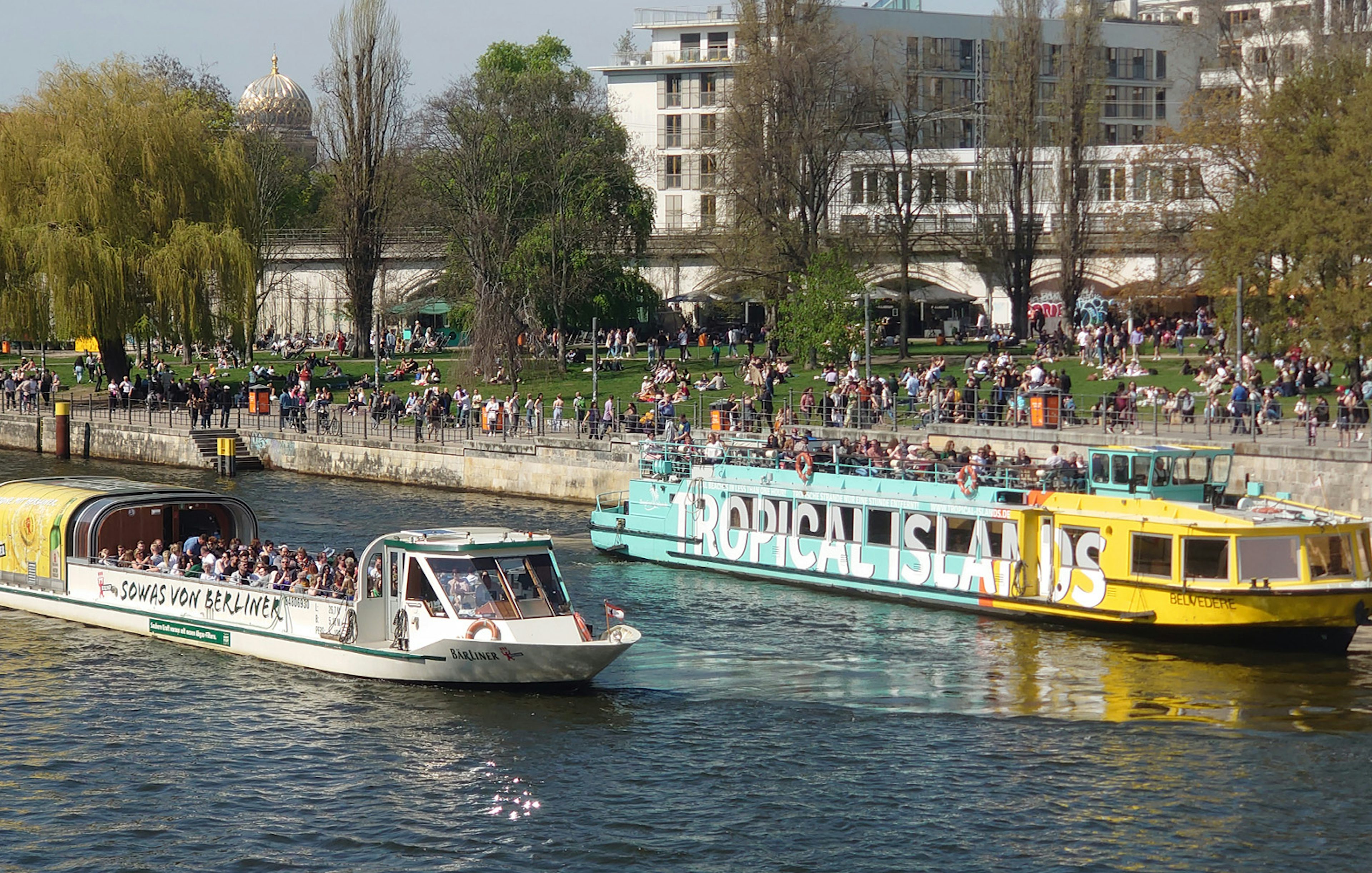 Sightseeing cruise boats on the River Spree in Berlin with people enjoying the view.