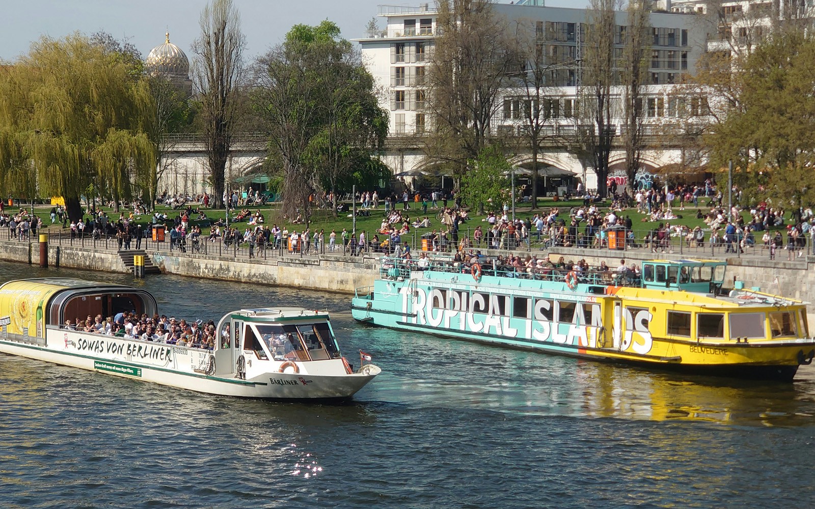 Sightseeing cruise boats on the River Spree in Berlin with people enjoying the view.