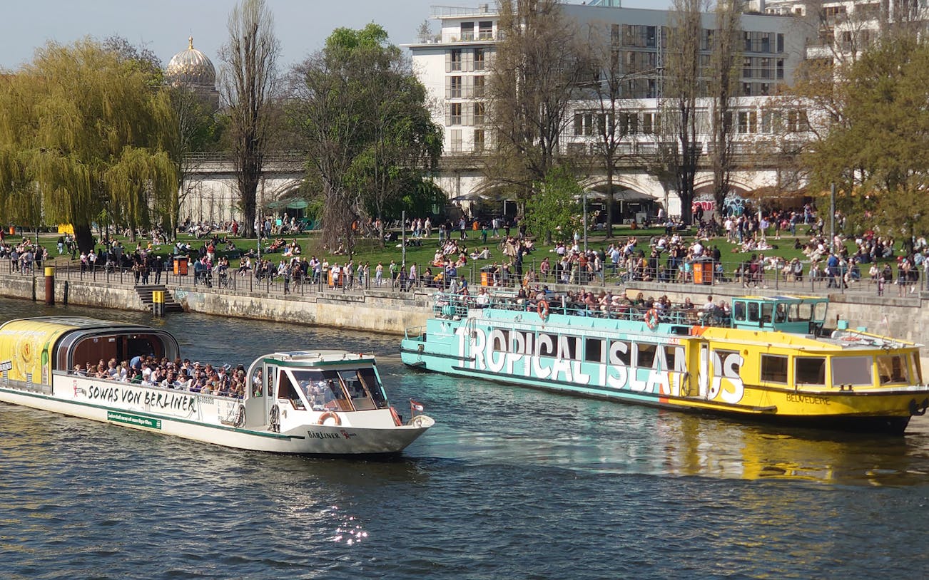 Sightseeing cruise boats on the River Spree in Berlin with people enjoying the view.