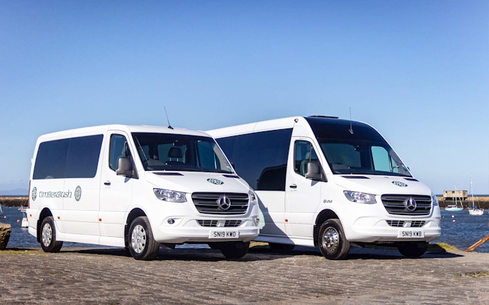 Private air-conditioned transfer vans parked by the waterfront in Edinburgh.