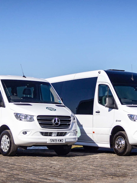 Private air-conditioned transfer vans parked by the waterfront in Edinburgh.