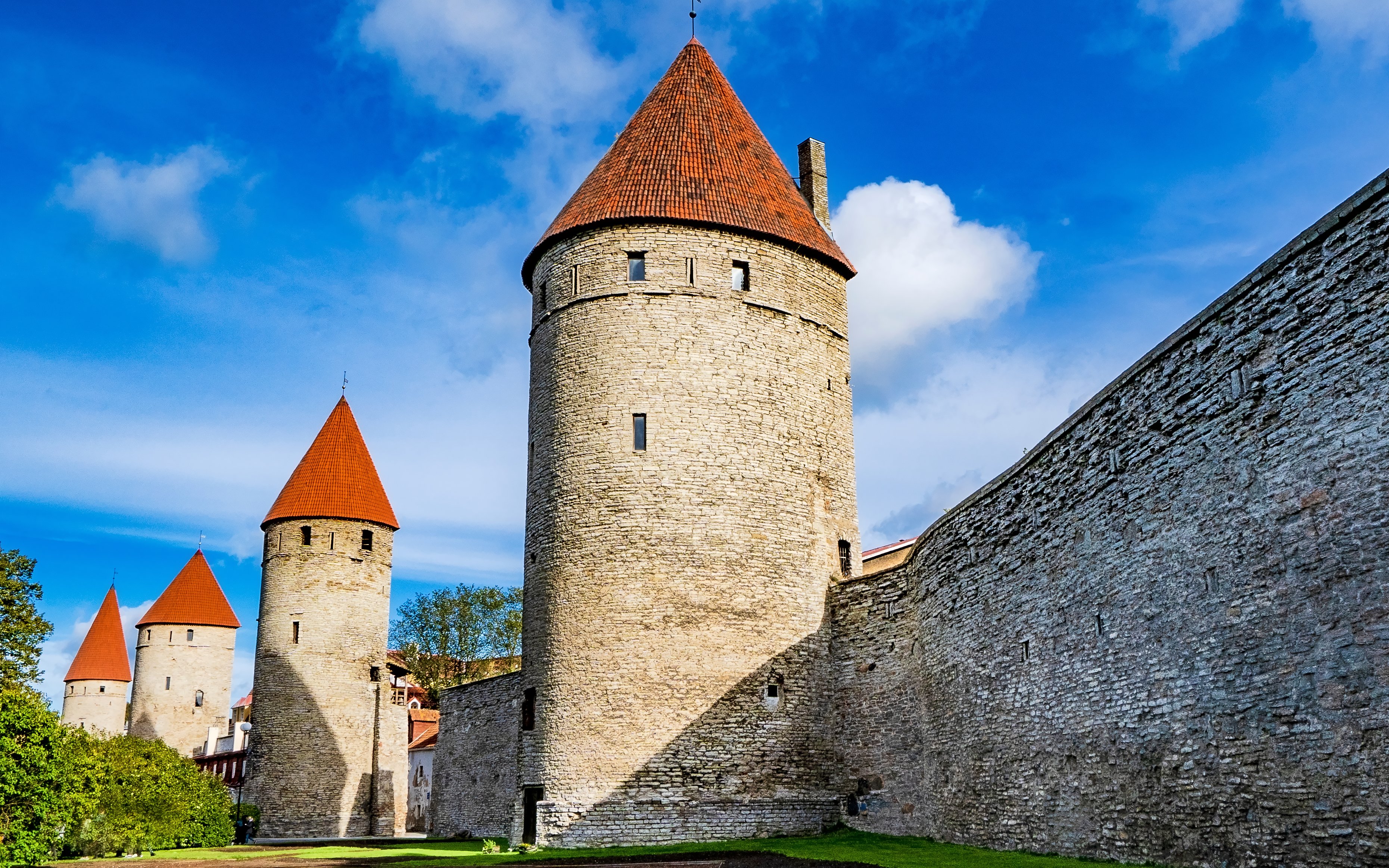 Tallinn Old Town city walls with red-roofed towers under a blue sky.