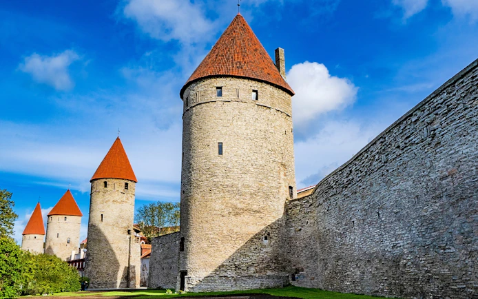 Tallinn Old Town city walls with red-roofed towers under a blue sky.