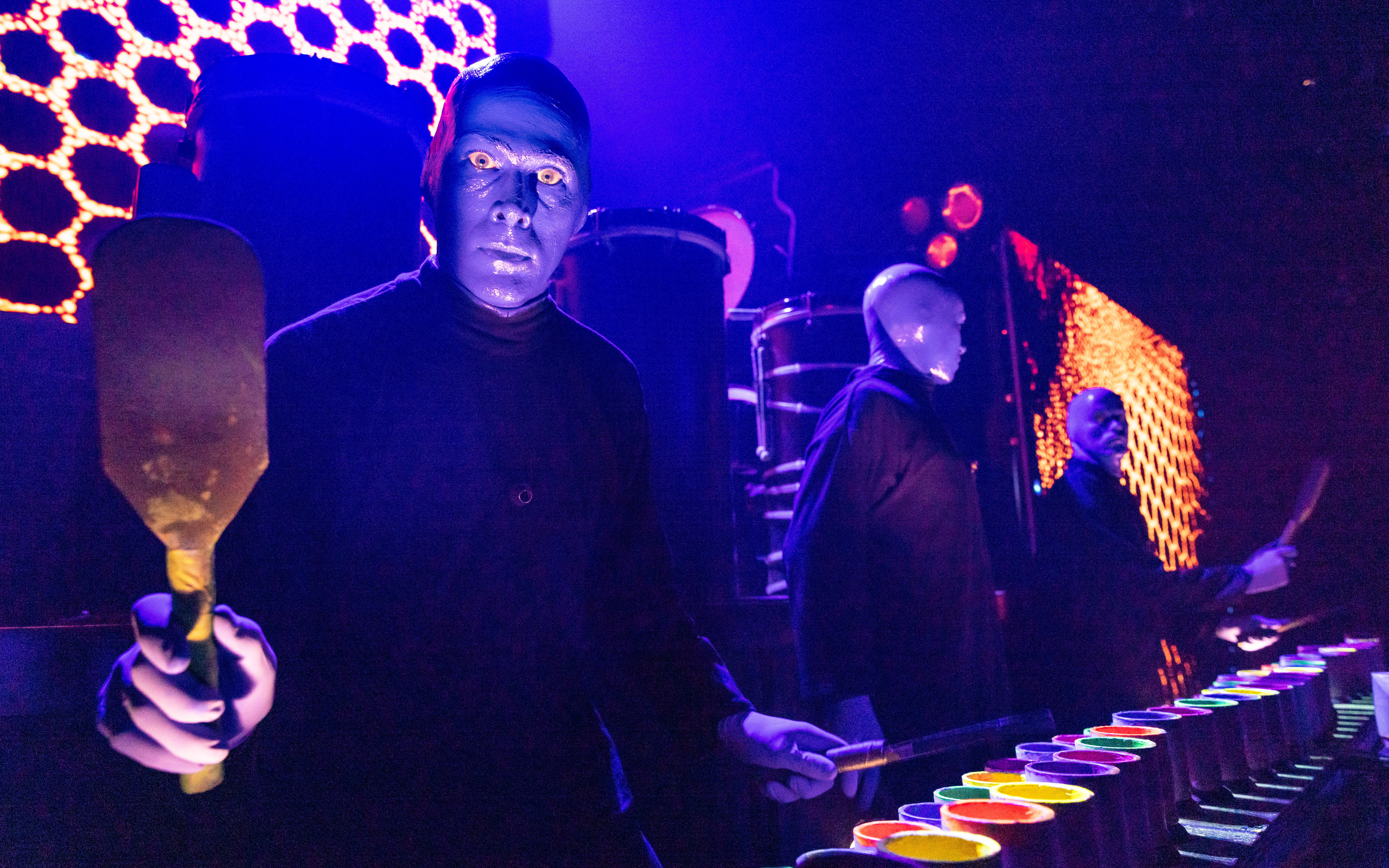 Blue Man Group performing with colorful drums on stage in Orlando.