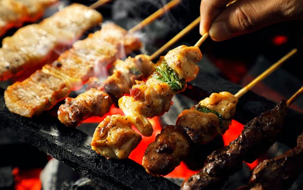 Yakitori skewers grilling over charcoal embers in Japan.