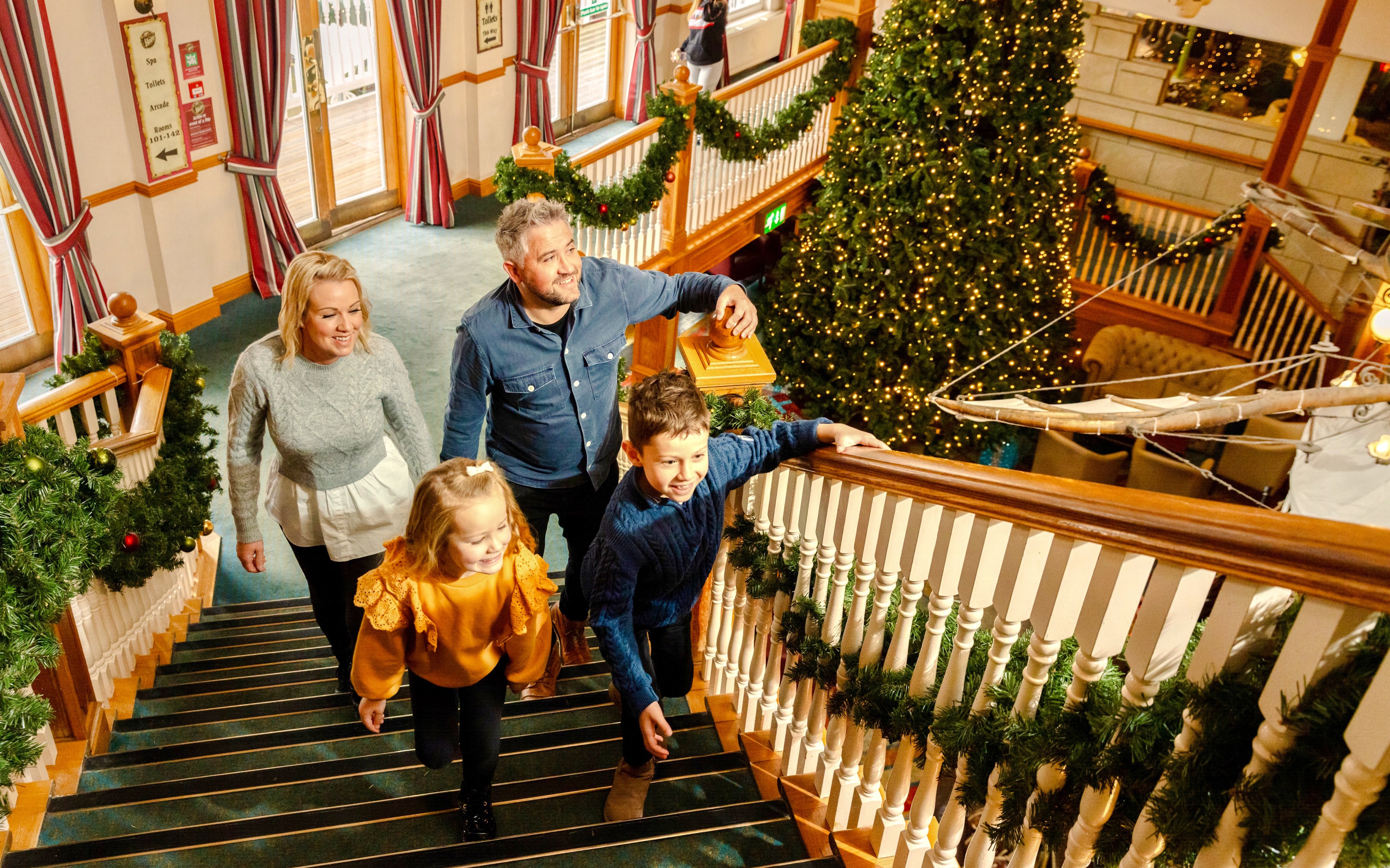 Family walking up decorated staircase at Alton Towers during Christmas season.