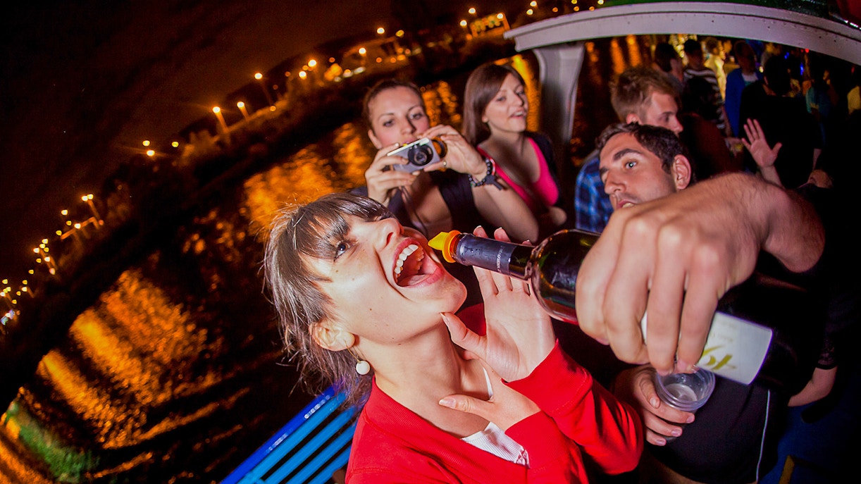 Prague boat party with people enjoying drinks and night views.