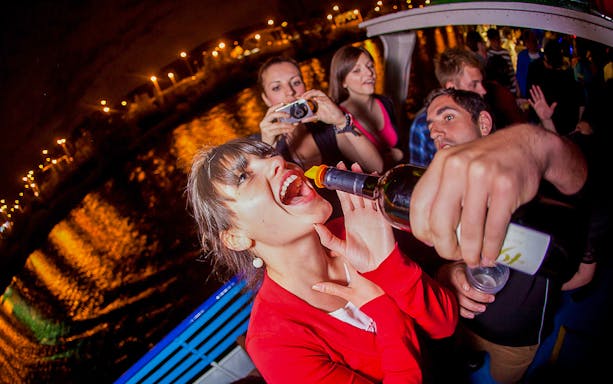 Prague boat party with people enjoying drinks and night views.